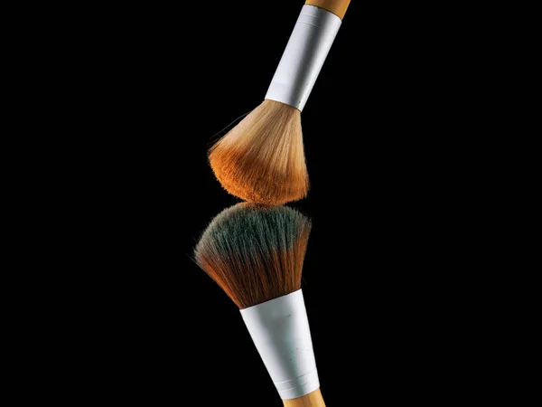 Escovas de maquiagem cosmética no fundo preto flash explosão respingo pó sombra blush . — Fotografia de Stock