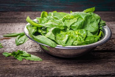 Ahşap arka plan üzerinde kase ıspanak yaprakları