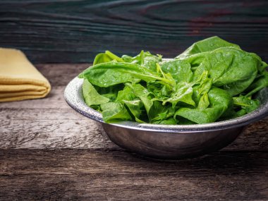 Ahşap arka plan üzerinde kase ıspanak yaprakları