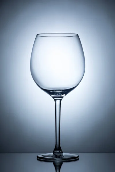 Um copo de vinho vazio para vinho tinto sobre fundo iluminado difusão — Fotografia de Stock