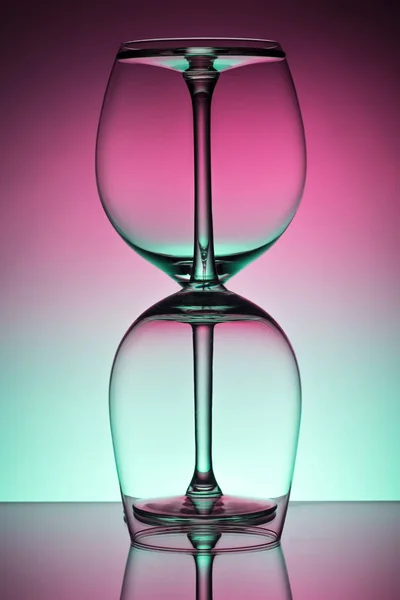 Dois copo de vinho vazio para vinho tinto sobre fundo iluminado difusão em composição abstrata com reflexão — Fotografia de Stock