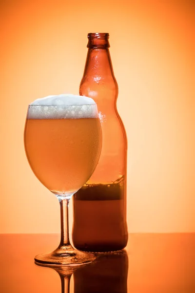 瓶啤酒和玻璃全泡沫凝析冷清爽静物在金色半透明的背景工作室拍摄 — 图库照片