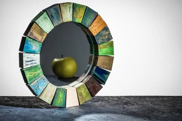 Espejo hecho a mano en un marco de madera textura agrietada pintura con reflexión manzana verde sobre la mesa — Foto de Stock