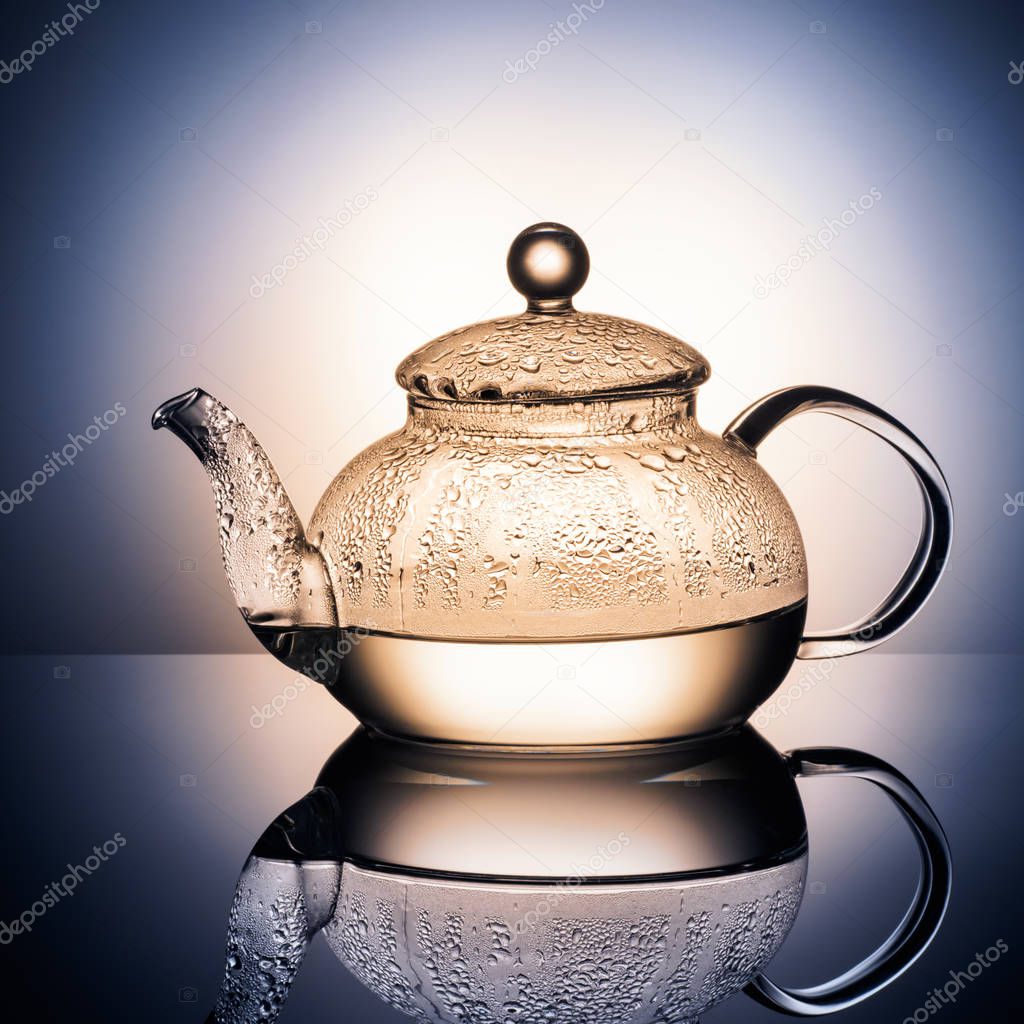 Glass teapot with boiling water and drops of condensation