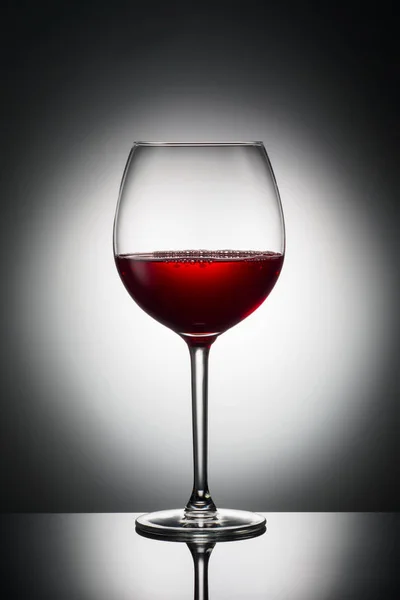 Large glass red wine shape of dark from grapes alcoholic beverage on luminous background advertising shot — Stock Photo, Image
