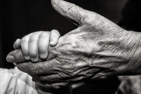 Childs'ın el ve eski buruşuk deri palmiye parmak kavramı fikrini seviyorum aile koruma çocuklar ve yaşlılar büyükbaba veya büyükanne arkadaşlık beraberlik ilişki iki nesil siyah ve beyaz vintage retro tarzı yakın çekim.