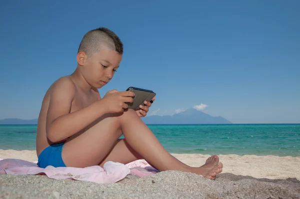 Junge spielt Smartphone-Strand — Stockfoto