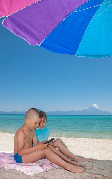 玩智能手机海滩阴影的小男孩女孩 — 图库照片