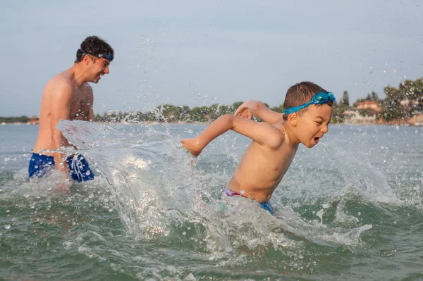 男孩儿子父亲玩海飞溅 — 图库照片
