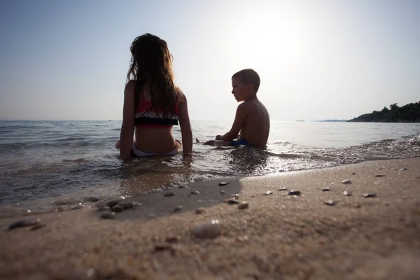 Τα παιδιά κάθονται στη θάλασσα νερό παραθεριστικές κατοικίες — Φωτογραφία Αρχείου