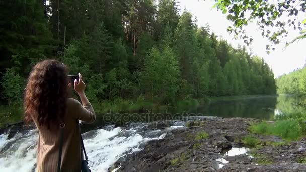 Женщина фотографирует лесную реку — стоковое видео
