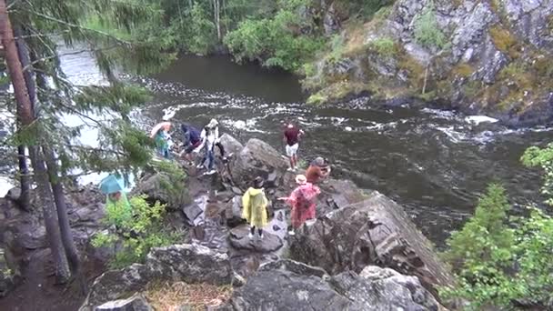 Människor gå på klippor vid en flod — Stockvideo