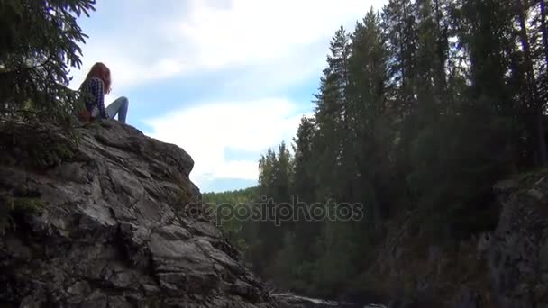 Bir uçurumun üzerinde oturan Kızıl saçlı kadın — Stok video