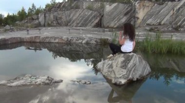 Bir havuzda bir kayaya oturan kız