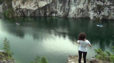 Bir uçurum yanında bir göl üzerinde duran kadın