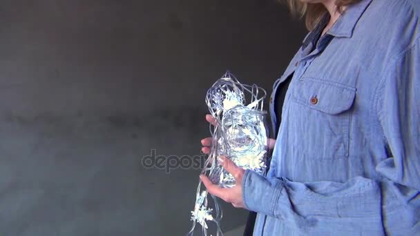 Woman holds fairy lights in her hands. — Stock Video