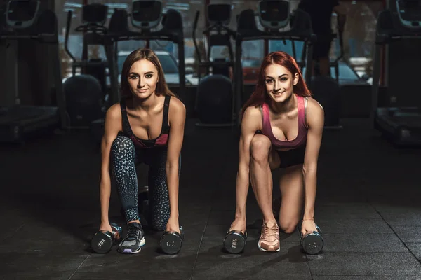 iki güzel fitness sportif genç kız lunges spor salonunda dumbbells ile yapıyor