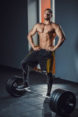 bekleyen ve ağır kameraya bakarak halter kaldırma önce hazırlanıyor Avrupa beyaz atletik bir adam. spor salonunda poz. Halter Bent.