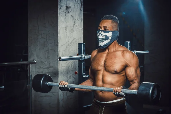 pazı üzerinde halter kaldırma maskeli kas genç Afro-Amerikan adam. Pazı ile Halter egzersiz. spor salonunda zenci adam