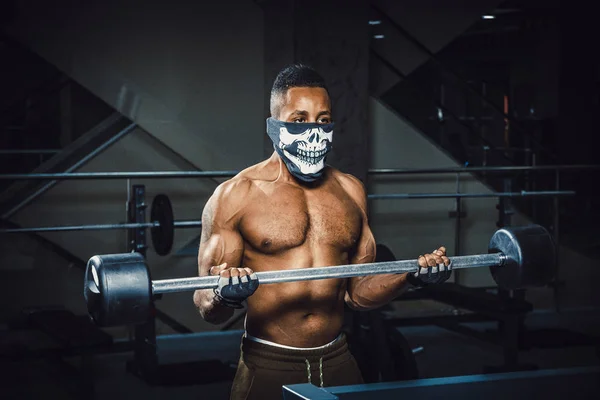 pazı üzerinde halter kaldırma maskeli kas genç Afro-Amerikan adam. Pazı ile Halter egzersiz. spor salonunda zenci adam