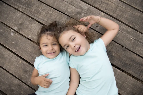 Abrazando hermanas en camisetas azules sobre tierra de madera —  Fotos de Stock