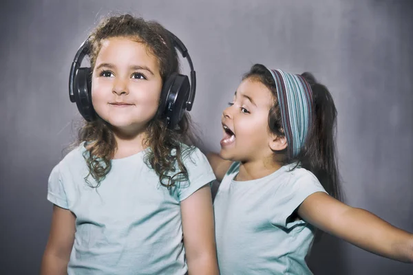 Uśmiechnięte dziewczyny, słuchanie muzyki w słuchawkach z siostrą krzyk — Zdjęcie stockowe