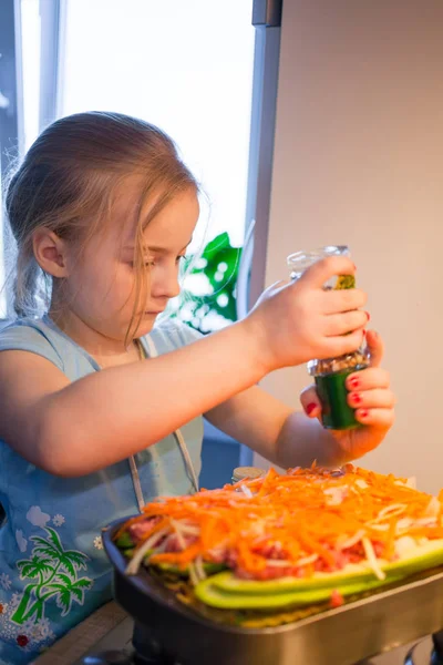 Маленькая девочка готовит лазанью — стоковое фото