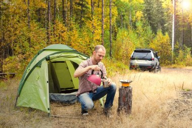 Onun kamp sonbahar ormandaki oturan adam