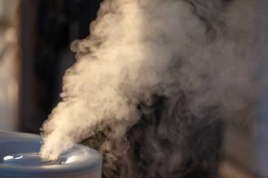 Nemlendirici akşam ışığında buhar yayıyor.