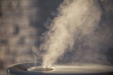 Nemlendirici beyaz tuğlalı arka planda buhar yayıyor. Çatı katı biçimi. 