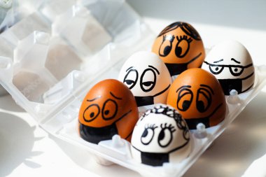 Farklı boyalı yüzleri ve tıbbi maskeleri olan yumurtalar.