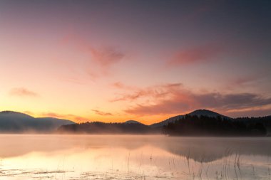 Sisli göl kenarında kırmızı şafak