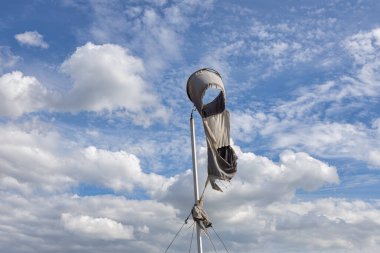 Bulutların arkasındaki havaalanı için rüzgar göstergesi. Rüzgâr tarafından parçalanmış.