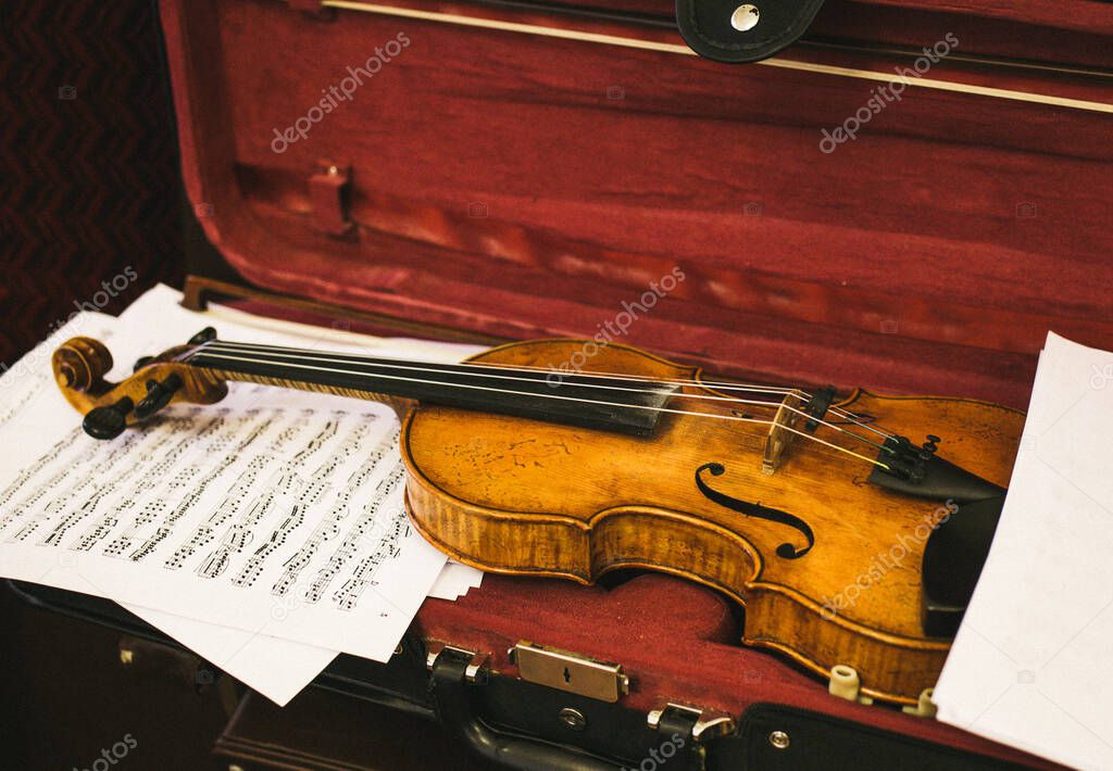 the violin is in the case , next to the sheet music, retro, vintage