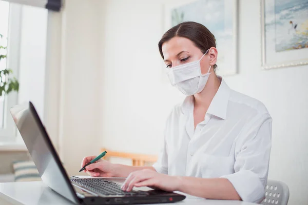 Coronavirus. Business woman working from home wearing protective mask. Business woman in quarantine for coronavirus wearing protective mask. Working from home.