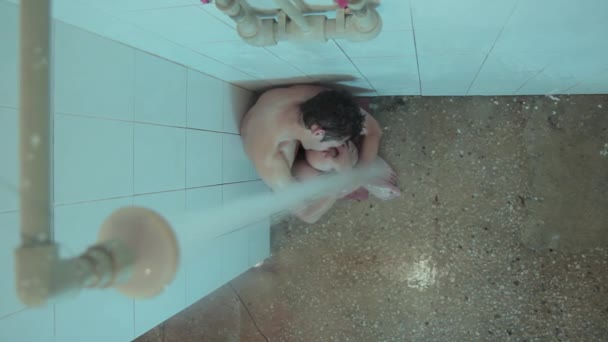 Um homem senta-se debaixo do chuveiro — Vídeo de Stock