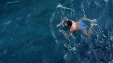 bir adam denizde yüzüyor.