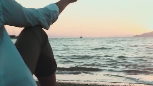 Mannen på stranden kasta stenar i havet — Stockvideo