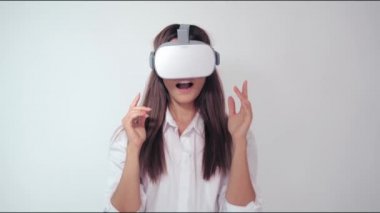 Sanal gerçeklik kulaklığı kullanan mutlu tatlı kız. Sanal gerçeklik oyunu. Beyaz arka planda VR kulaklık takan bir kadın. Güzel bir kadın modern VR gözlükleri kullanarak bir şeye dokunur.