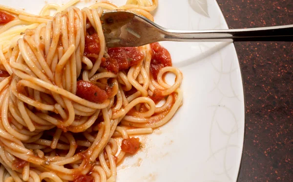 Спагетти в томатном соусе на тарелке с вилкой — стоковое фото