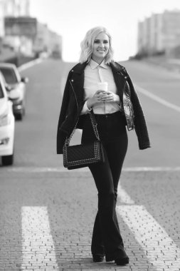Moda trendy kıyafetler kadın yolun çapraz güzel ve bir fincan kahve ile sokakta yürüyen