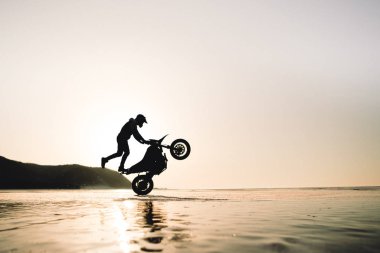 Motosikletle buz üstünde oynayan adam.
