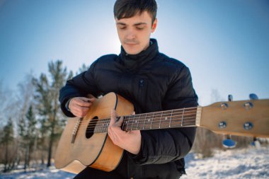 Sibirya 'da güneşli bir günde ormanda gitar çalan bir adam.