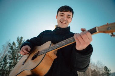 Sibirya 'da güneşli bir günde ormanda gitar çalan bir adam.