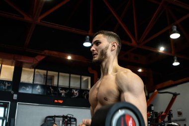 Yakışıklı sakallı adam spor salonunda antrenman yapıyor.