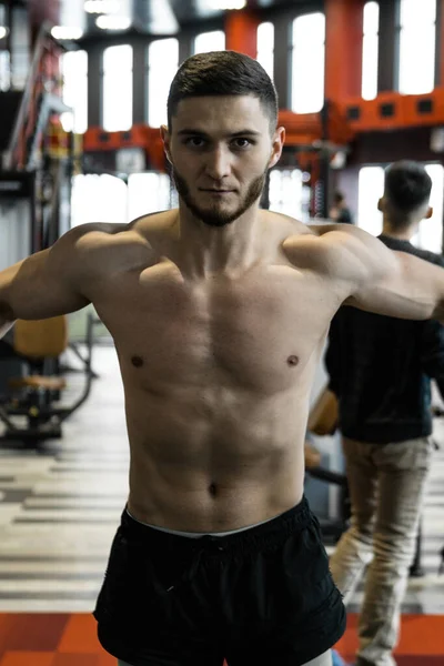 Yakışıklı sakallı adam spor salonunda antrenman yapıyor.