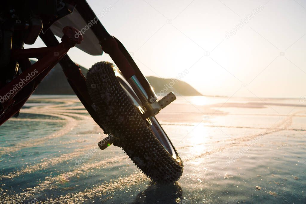 motorcycle wheel with spikes on ice in the sunset