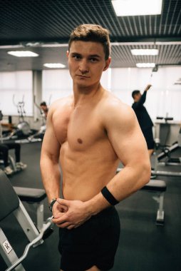 Yakışıklı kaslı adam spor salonunda poz veriyor. 