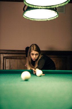 Kadın ışığın altında bilardo oynuyor
