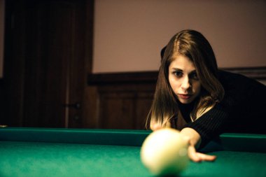 Kadın ışığın altında bilardo oynuyor
